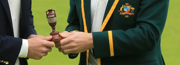 Cricket players from Australia and England hold the Ashes trophy in their hands