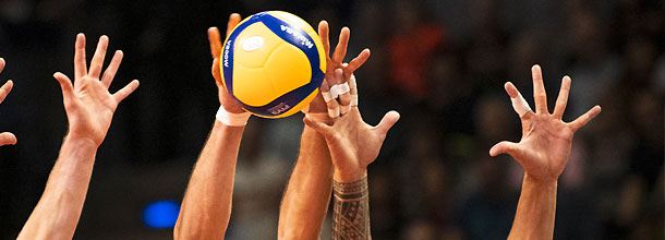 Volleyball-Spieler springen um den Ball am Netz